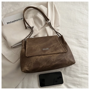 Detail of vintage brown textured shoulder bag with silver chain strap and metal clasp