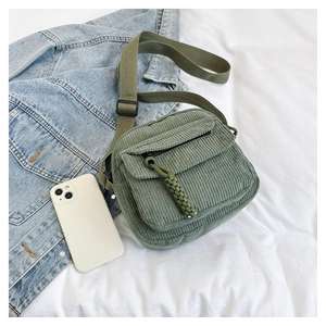 Detailed view of green corduroy shoulder bag with woven zipper pull and adjustable strap