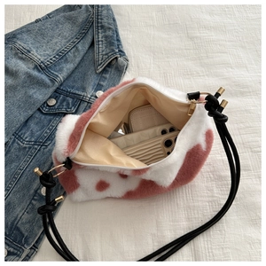 Top-down view of pink spotted plush bag interior showing phone storage and zip closure