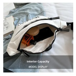 Détail montrant la capacité interne du grand sac banane blanc en toile sur du denim