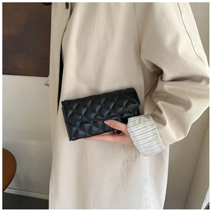 Classic black quilted leather long wallet shown held against a beige coat