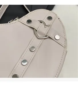 Détail macro d'une boucle coeur argentée et rivets sur un sac rose poudré