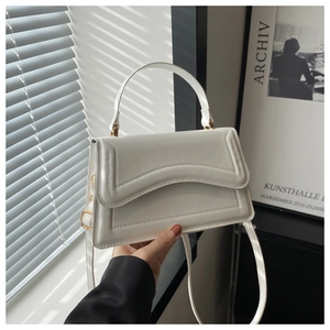 Chic white leather handbag detail with wavy stitched flap and gold metal hardware