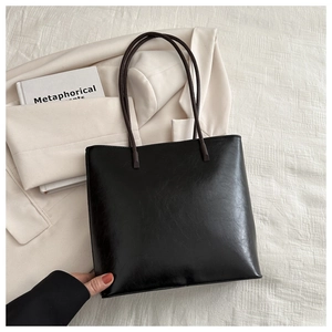 Minimalist black PU leather tote bag shown on stylish beige blazer and book backdrop