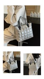 Detail of silver quilted puffer tote bag with black handles and metal texture finish