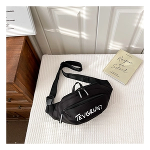 Détail du sac banane en toile noire avec lettrage blanc sur tissu blanc texturé