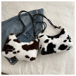 Detail of plush cow print shoulder bags in black and brown with woven rope straps
