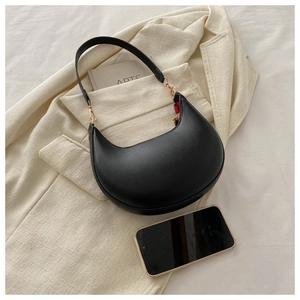 Detailed view of black PU leather underarm bag with gold hardware on a textured blazer