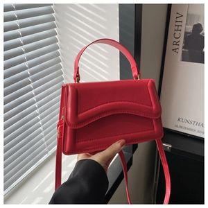 Detail view of red shoulder bag with gold hardware and stylish U-shaped stitching
