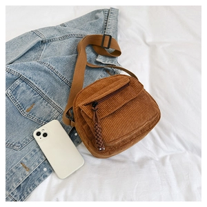 Detail of brown corduroy crossbody bag with adjustable strap on white background