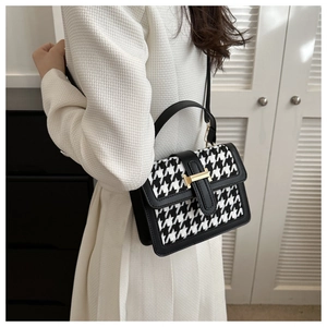 Detailansicht der gewebten Hahnentritt-Handtasche mit Lederbesatz und goldener H-Schnalle