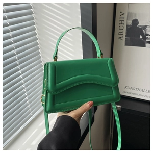 Close-up of bright green handbag with wavy quilted texture and gold hardware details