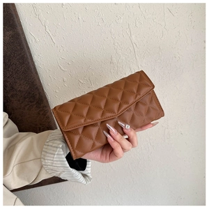 Detail of a brown quilted leather clutch bag with a sleek diamond stitched pattern