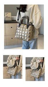 Détail du sac fourre-tout matelassé doré avec surpiqûres et poignées cylindriques