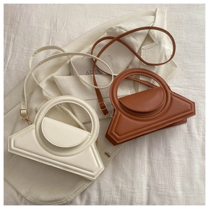 Detail view of cream and brown geometric handbags with round handles on soft fabric