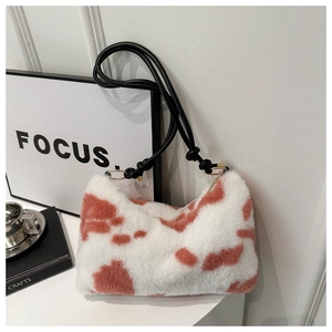 Detail of plush cow print underarm bag with black knot straps and gold hardware accents
