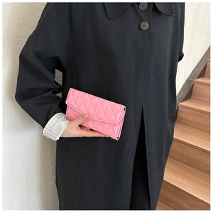 Pink quilted leather clutch bag held by model featuring classic rhombus stitching detail