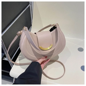 Detail of beige crescent bag with gold moon buckle and adjustable shoulder strap