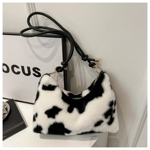 Detail shot of the plush cow print texture and leather strap on this stylish hobo bag