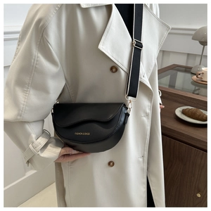 Détail du sac besace noir en cuir avec logo doré et large bandoulière en toile