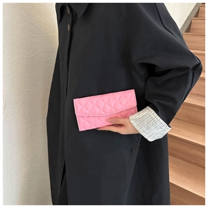 Pink quilted long wallet held by a model in a dark coat for a stylish color contrast