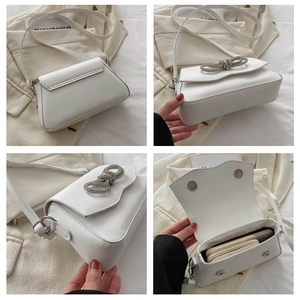 Detail view of white PU leather crossbody bag featuring a silver rhinestone bow and magnetic closure