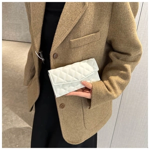 Close-up of white quilted long wallet with classic diamond pattern held by a model