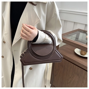 Detail of dark brown leather handbag with round handle and adjustable shoulder strap