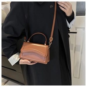 Close-up of brown vintage leather crossbody bag with wave stitching and metal buckle