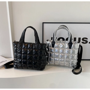 Detail of black and silver quilted down tote bag with adjustable shoulder strap and handles