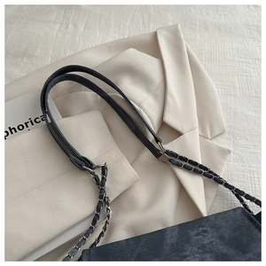 Detail of gray washed denim shoulder bag with silver metal chain strap on beige blazer