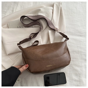 Close-up of brown PU leather dumpling bag with textured surface and geometric strap