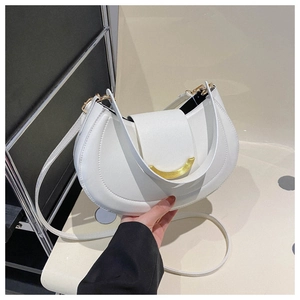 Close-up of a white half-moon shoulder bag with a gold smiley face clasp and fine stitching