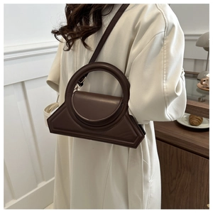 Detail of dark brown geometric tote bag with round handle and thin shoulder strap