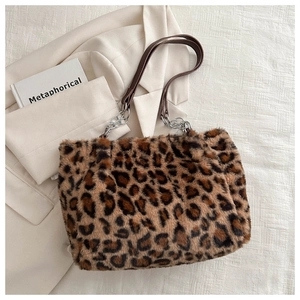 Detail of plush leopard print shoulder bag with silver metal chain on textured background