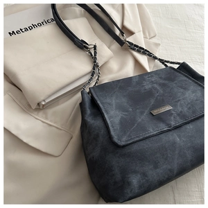 Detail of dark grey marble texture shoulder bag with metallic logo and chain strap