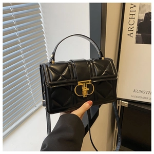 Close-up of black quilted leather handbag with gold metal clasp and hand-held detail