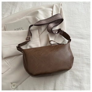 Detail of dark brown lychee texture leather bag with a vintage woven shoulder strap