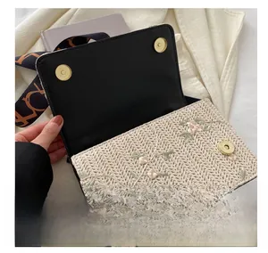 Detail of floral embroidery and gold magnetic buckles on a woven summer crossbody bag