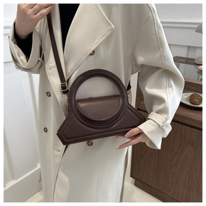 Close-up of a minimalist dark brown geometric handbag featuring a circular top handle
