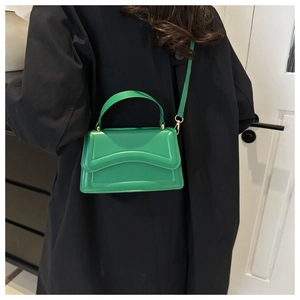 Detail view of a bright green crossbody bag with wavy quilted patterns and gold hardware
