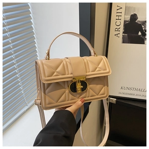 Detail of beige quilted faux leather handbag with gold oval twist lock and slim strap