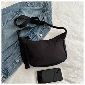 Detailed top view of black nylon crossbody bag with adjustable strap on denim fabric
