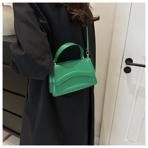 Detail of bright green mini crossbody bag with wavy flap design and gold hardware
