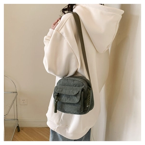 Detail of dark green corduroy crossbody bag featuring a textured finish and wide strap