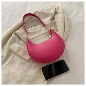 Chic magenta PU leather crescent shoulder bag placed on a beige blazer with gold hardware