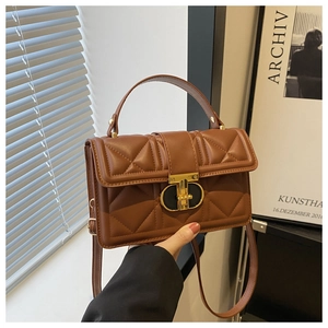 Detail view of brown quilted handbag featuring diamond pattern and gold metal clasp