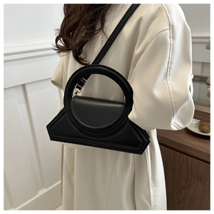 Detail shot of a black matte geometric handbag with a round handle and silver hardware