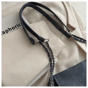 Close-up of grey denim texture and metal chain strap on minimalist shoulder bag