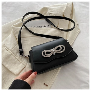 Close-up of black crossbody bag featuring a silver rhinestone bow on the front flap